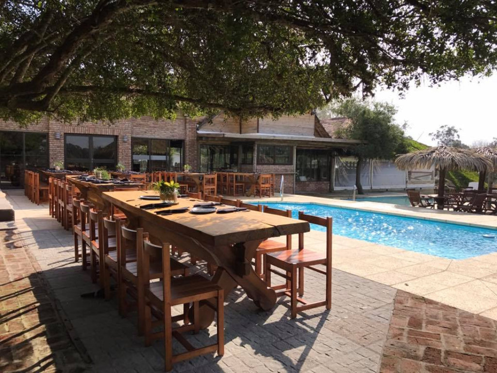 Mesas listas para el almuerzo al lado de la piscina en Rafaella ChacraEventos durante el día, listas para el evento empresarial