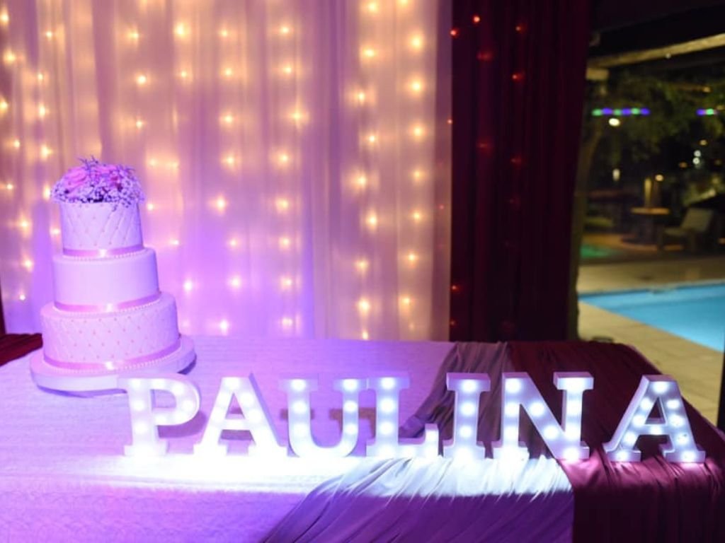 Torta de cumpleaños decorativa junto a un cartel con el nombre de la cumpleañera en Rafaella ChacraEventos