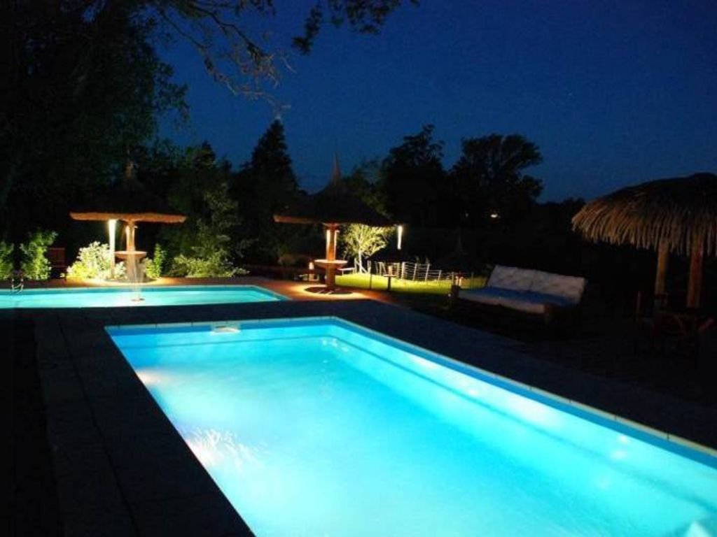 Piscina iluminada de noche en Rafaella ChacraEventos, creando un ambiente relajante y mágico
